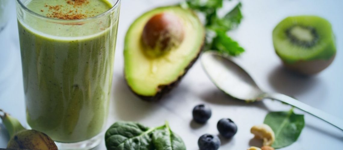 Green-smoothie-surrounded-by-fruit-and-nuts